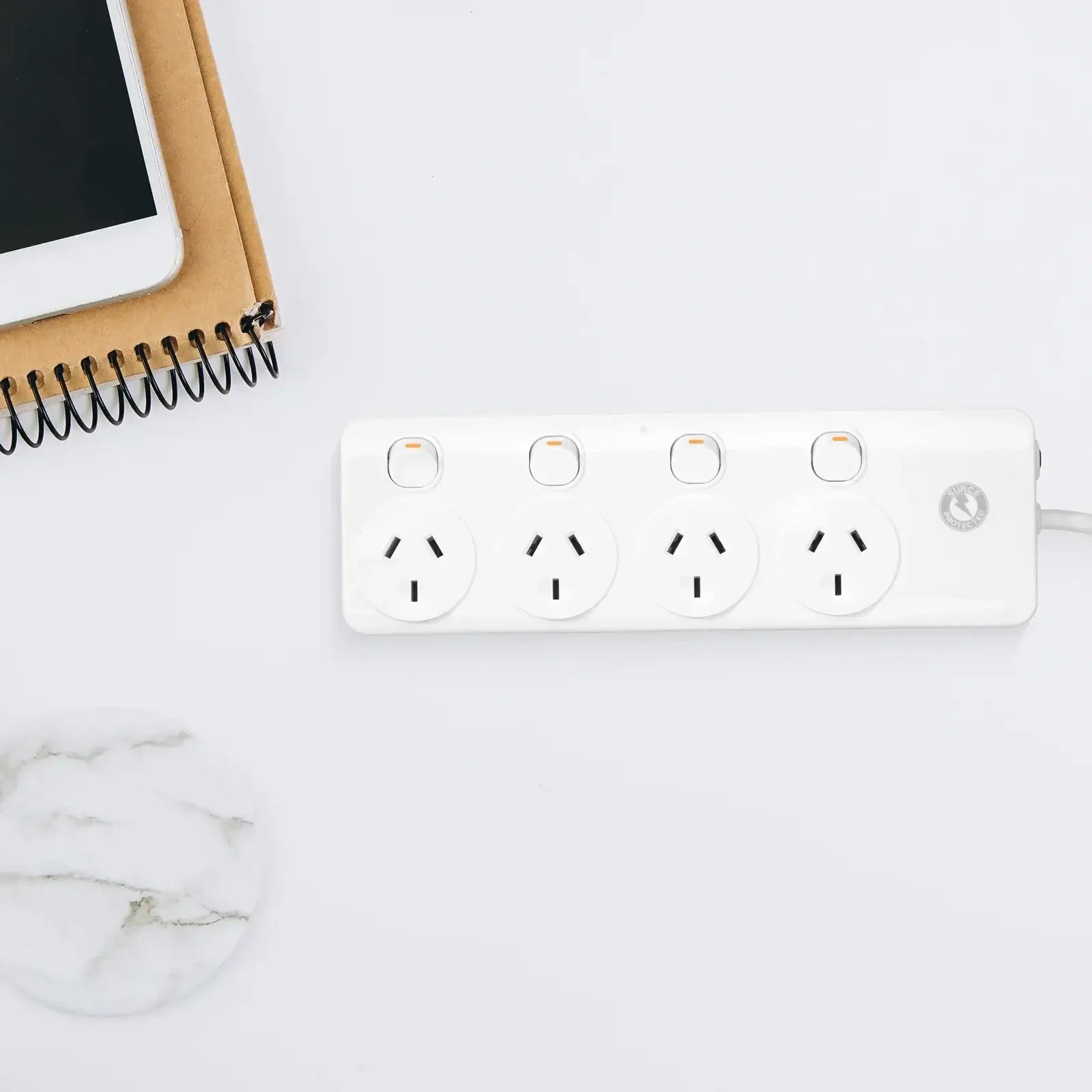 Four outlet surge protector power board with switches on white desk