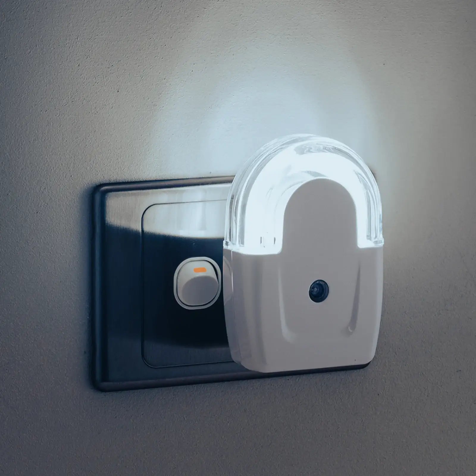 Plug-in LED night light with sensor on a wall power outlet, illuminated in a dark room
