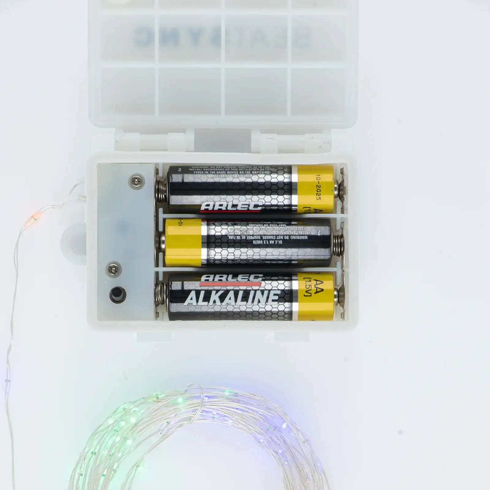 Battery pack with three AA alkaline batteries powering LED string lights on white background