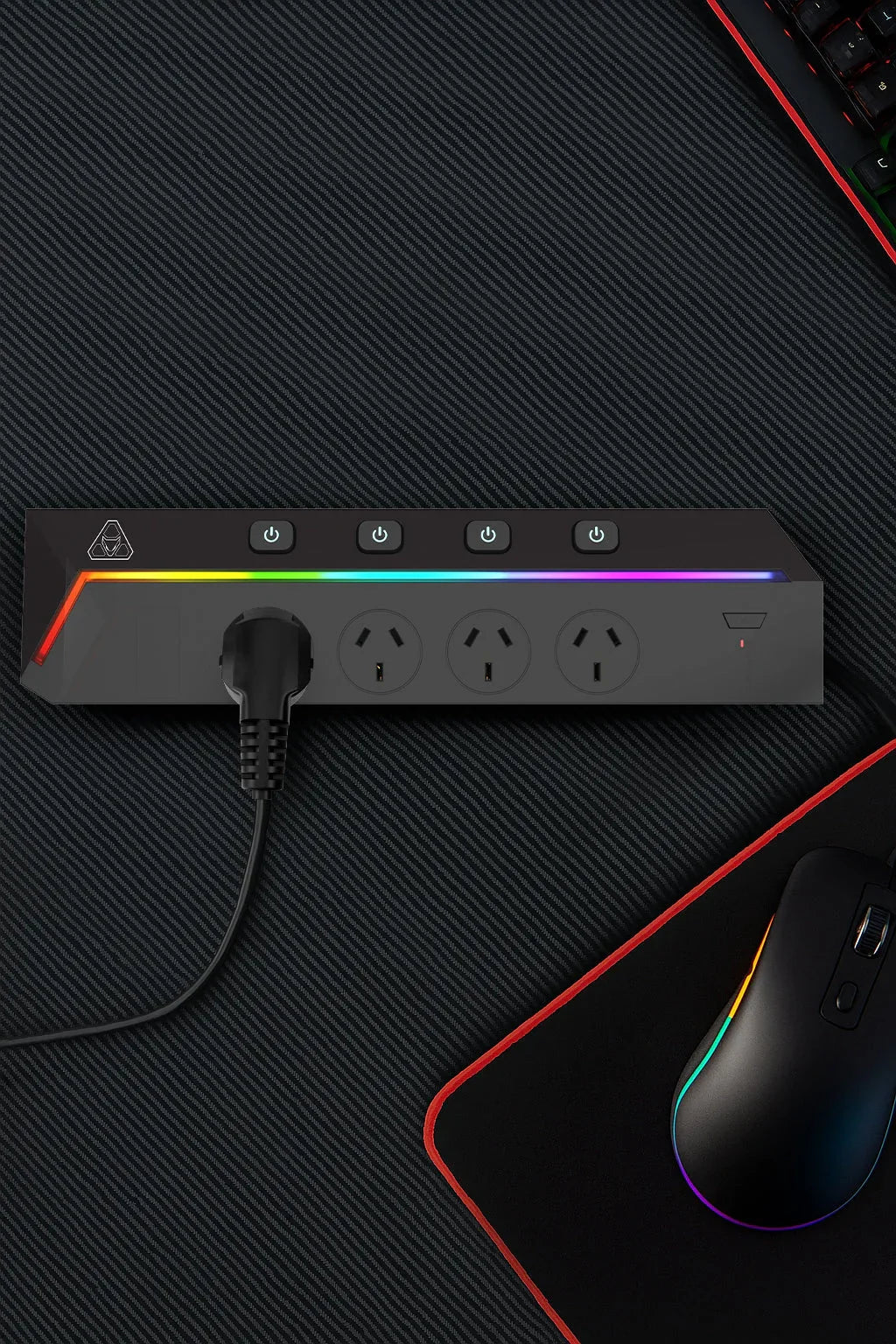 RGB gaming power strip with three outlets and four switches on a black desk with mouse and keyboard