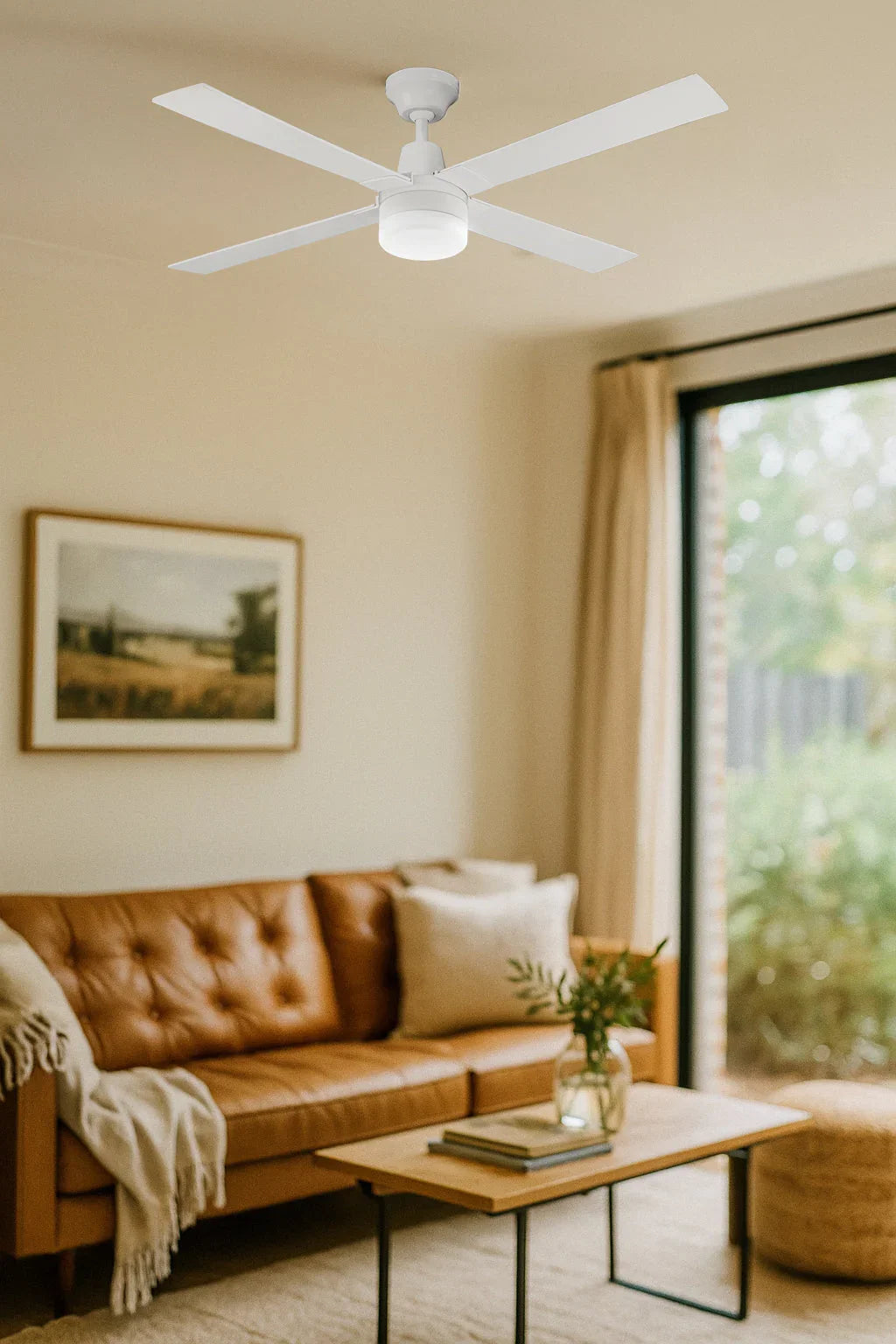Modern white ceiling fan with light in cozy living room with tan sofa and large window
