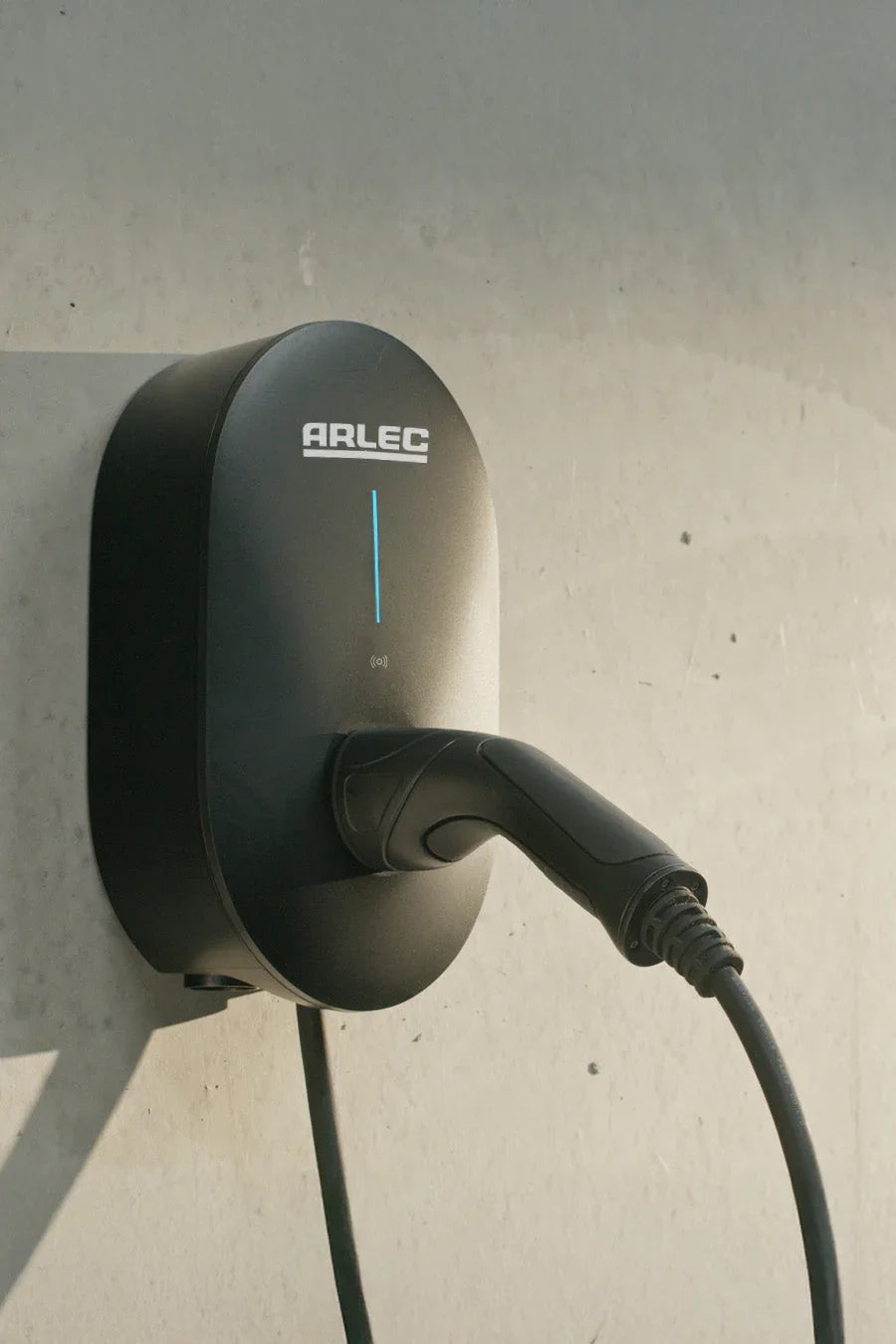 Wall-mounted ARLEC EV charger with charging cable against a concrete wall