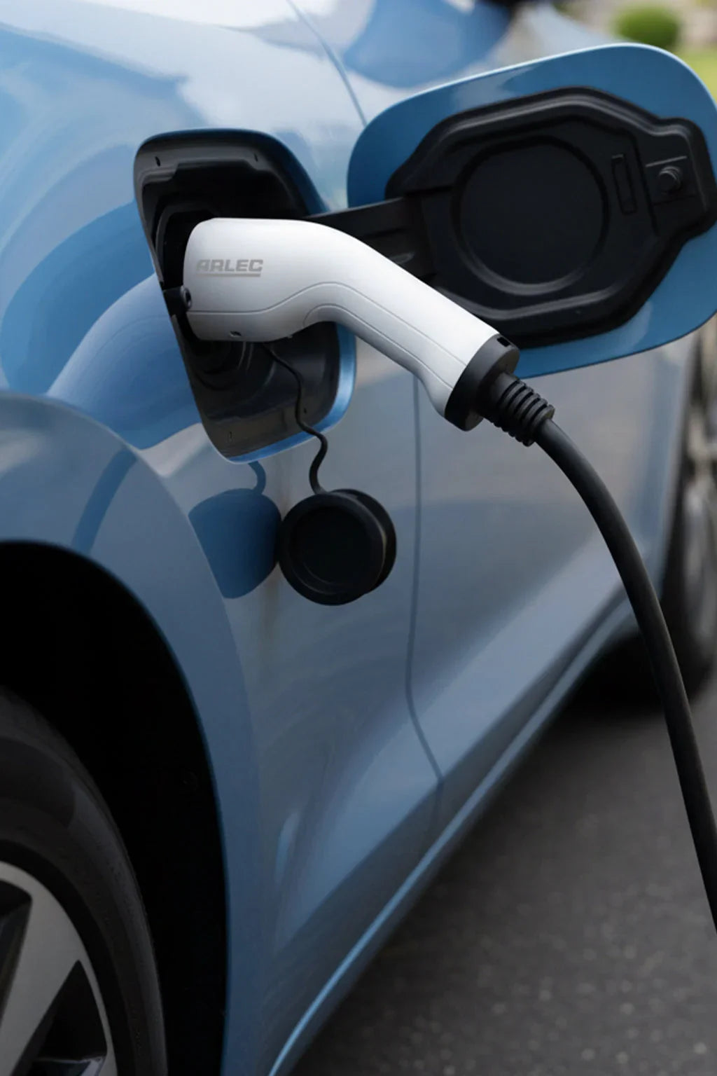 Electric car charging with EV cable plugged into a blue vehicle on a street