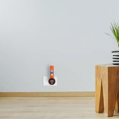 Orange safety plug lock device on wall outlet in modern living room with wooden table and plant
